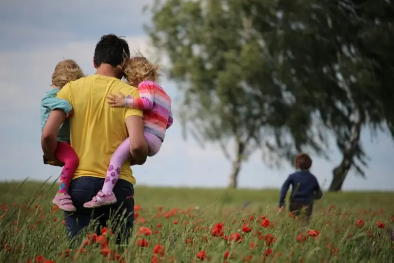 Vater geht mit Kindern durch ein Feld